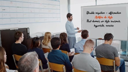 Classe d’adultes en formation sur la double négation face au tableau blanc et à leur formateur